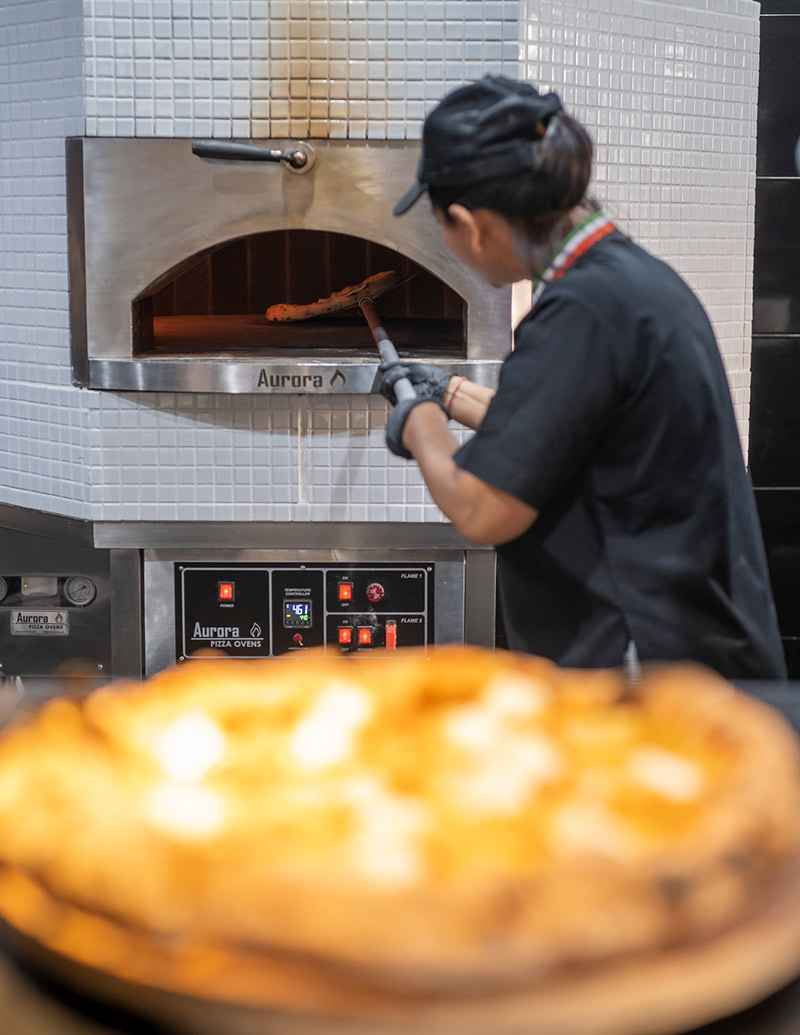Cooking pizza in The Village Cucina Italiana