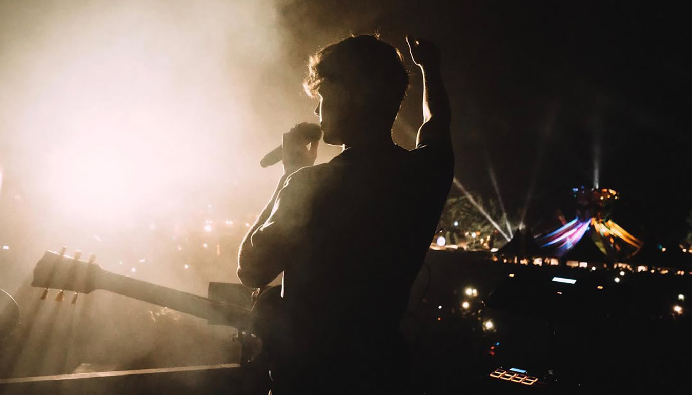 Petit Biscuit with the guitar and microphone on the stage