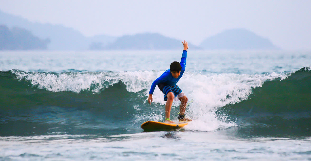 A boy is cahtching the wave in Impossible Surf School