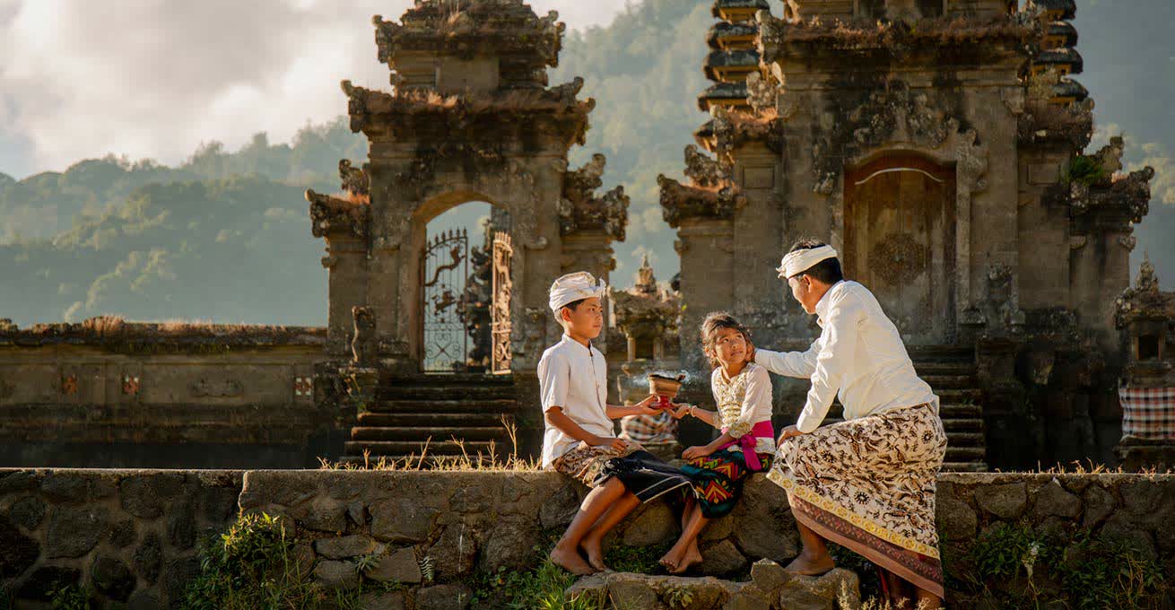 Indonesian family in traditional dresses doing the ritual near the temple