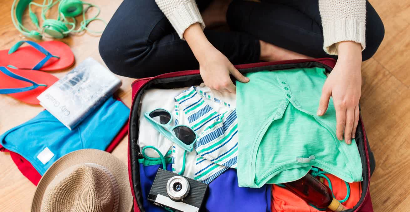Woman is packing the suitcase for traveling to Bali