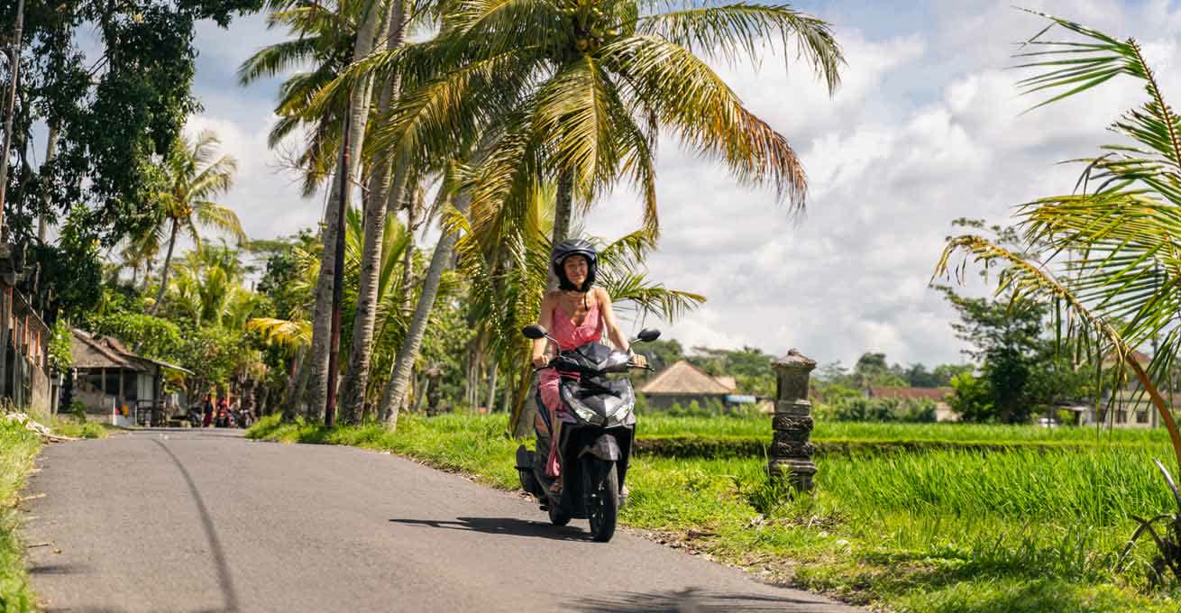 Woman is traveling by motorbike in Bali