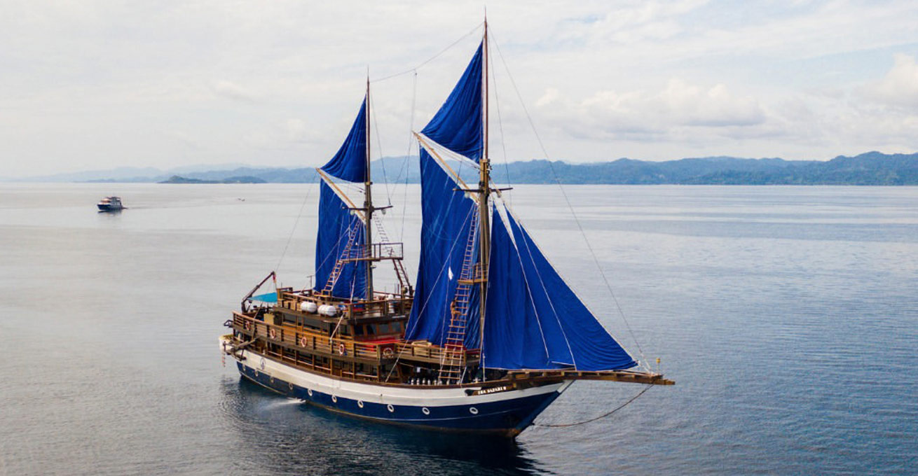 Yacht with blue sails rented from Pulau Private Charter