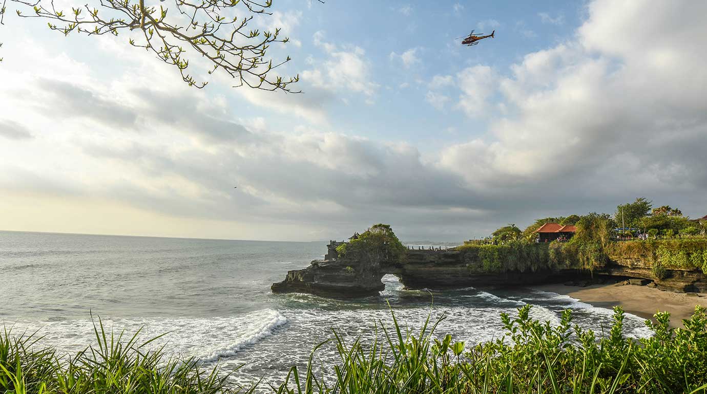 Helicopter flying over Tanah Lot Tmeple in Bali
