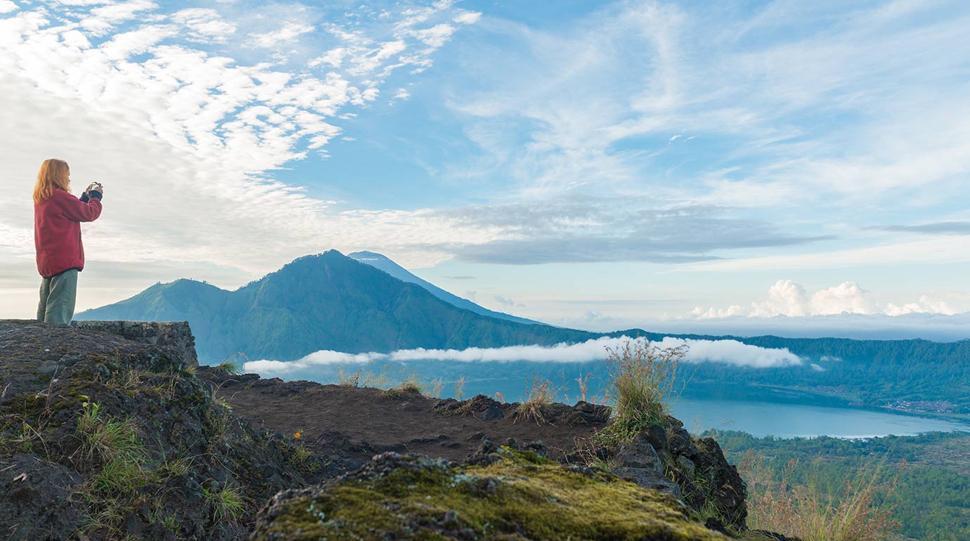 A woman takes a photo of Mount Batur