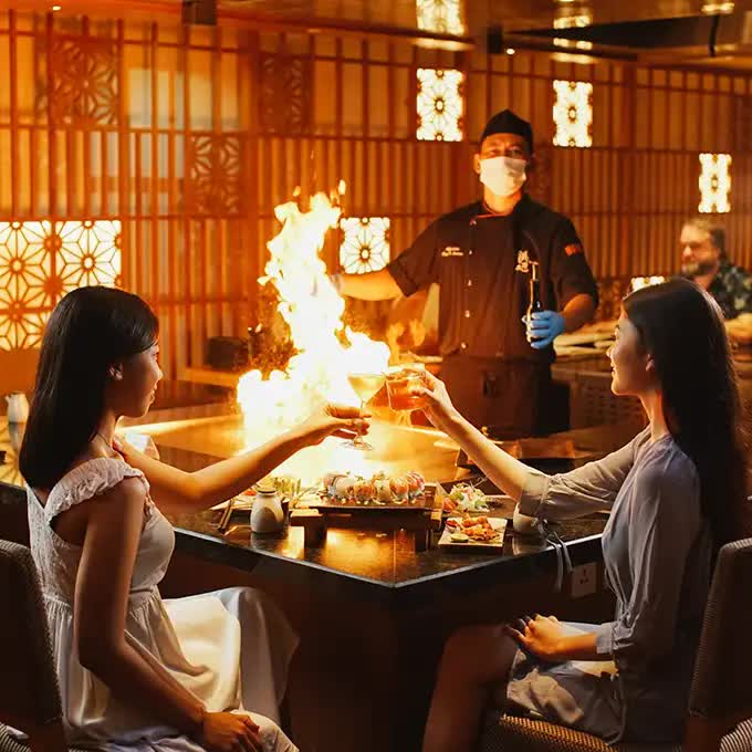 Two girls at a restaurant table and a fire show