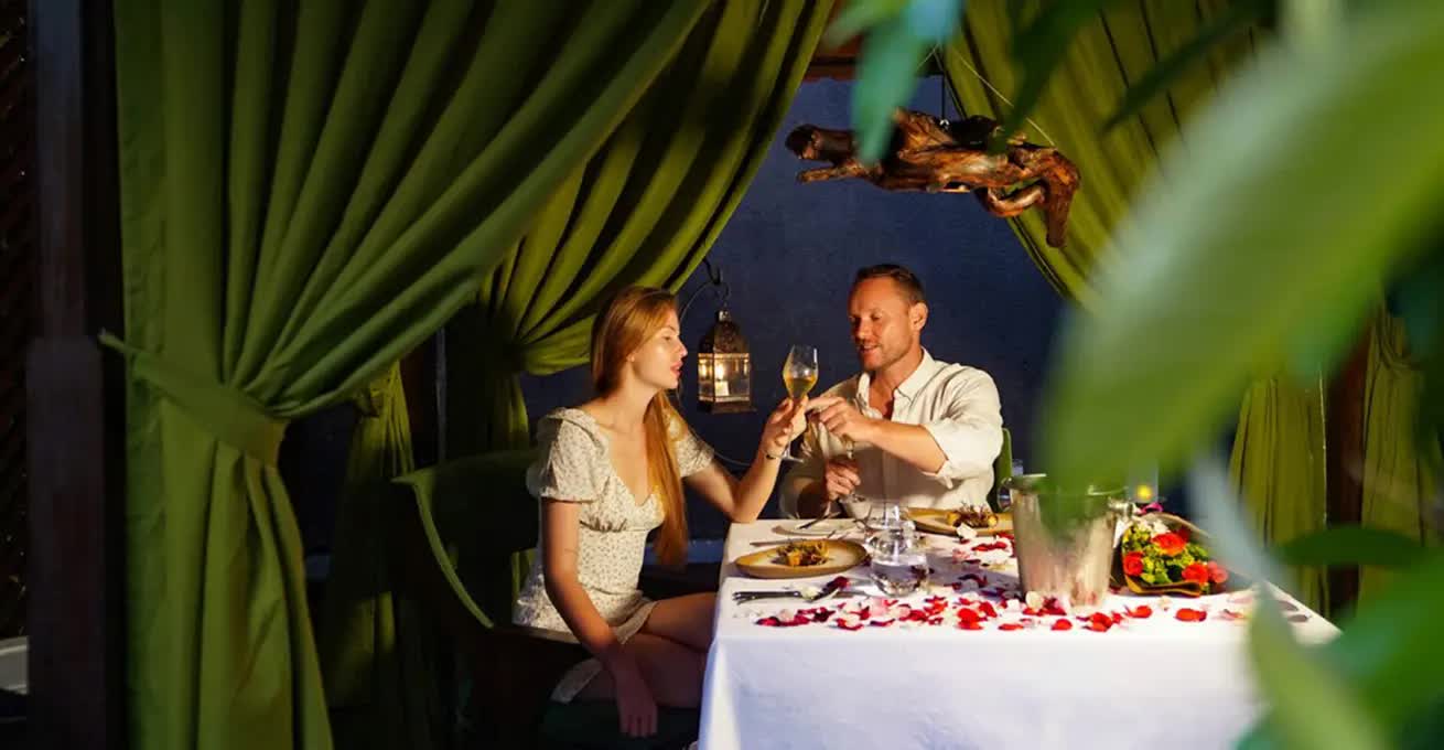 Young couple drinking and eating in a private dining room with green curtains at Mozaic restaurant