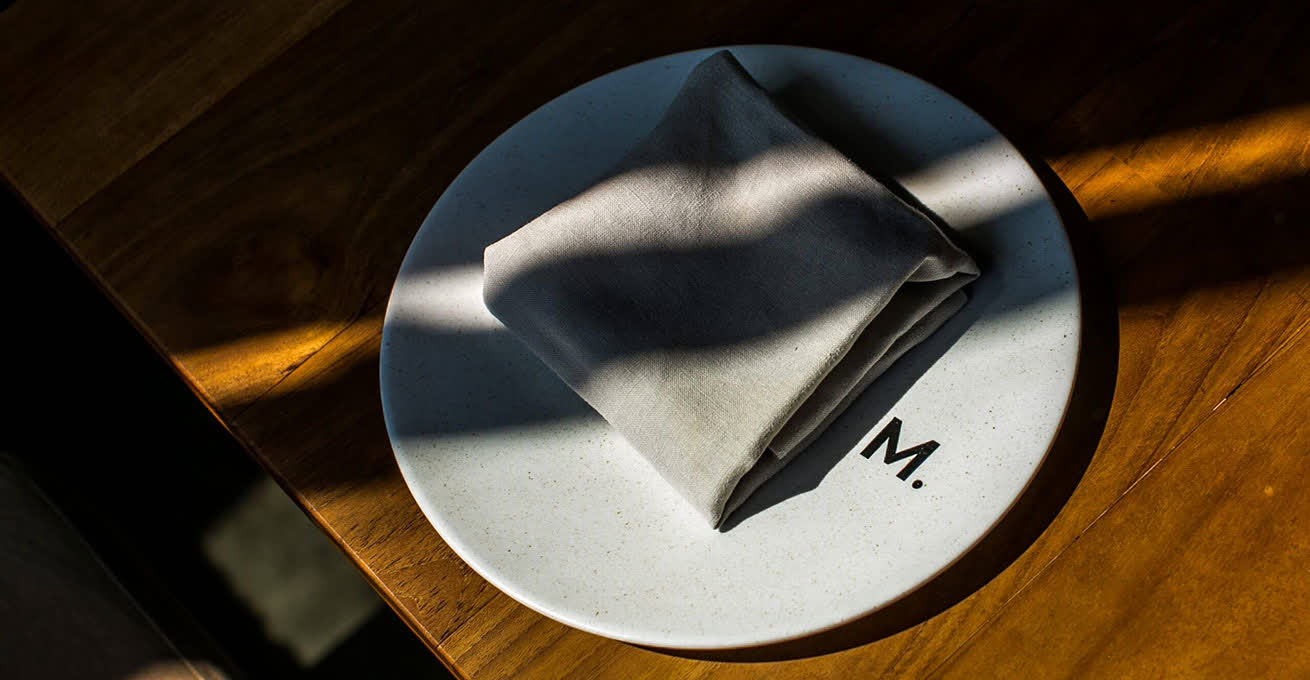 An empty plate with a napkin is lying on the table in a restaurant