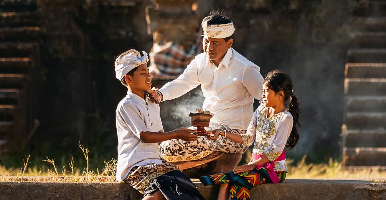 An Indonesian man is showing children the Balinese ritual.