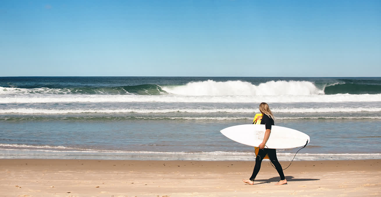 Woman is going to surf at Bingin Beach in Uluwatu