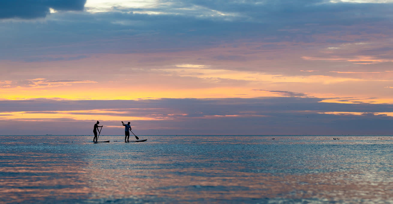The couple on teh SUP board during the Sunrise at Sanur Beach